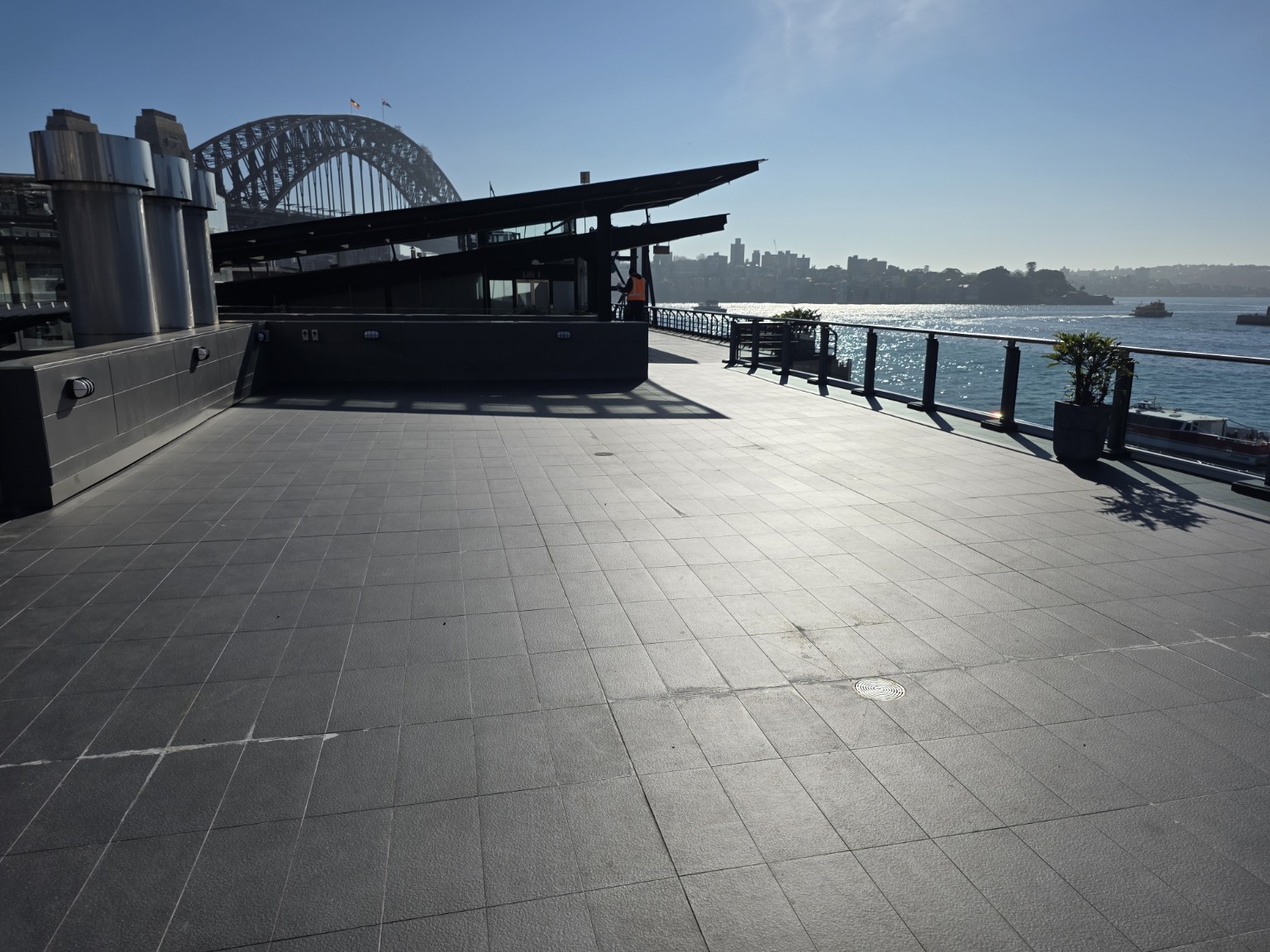 Open harbourfront terrace beside the Sydney Harbour Bridge on a clear day